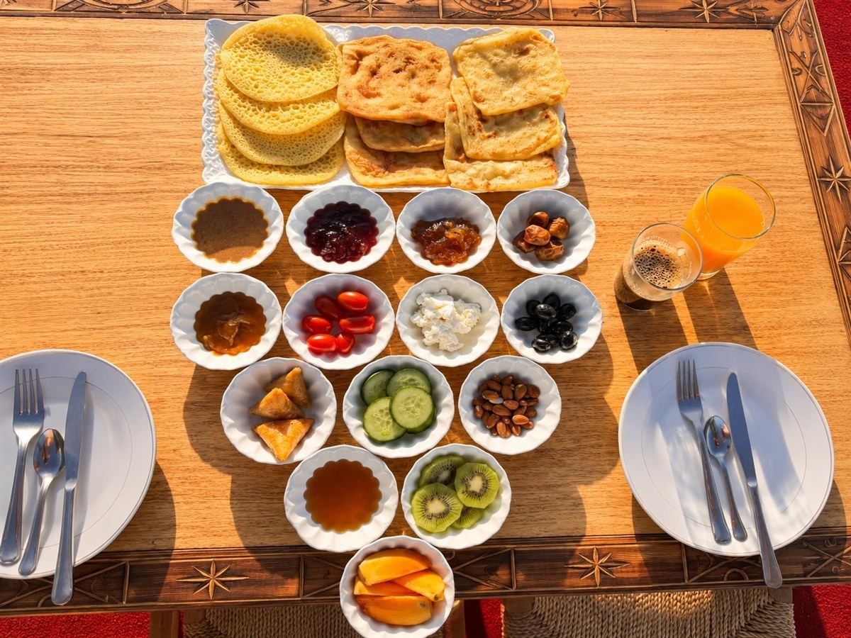 Traditional Moroccan breakfast: msemen, baghrir, honey, jams, dates, olives, cheese, almonds, fruit and orange juice